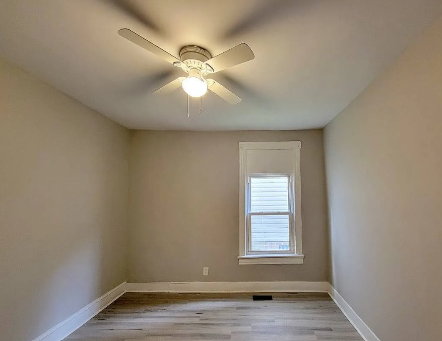 an empty room with a ceiling fan and a window