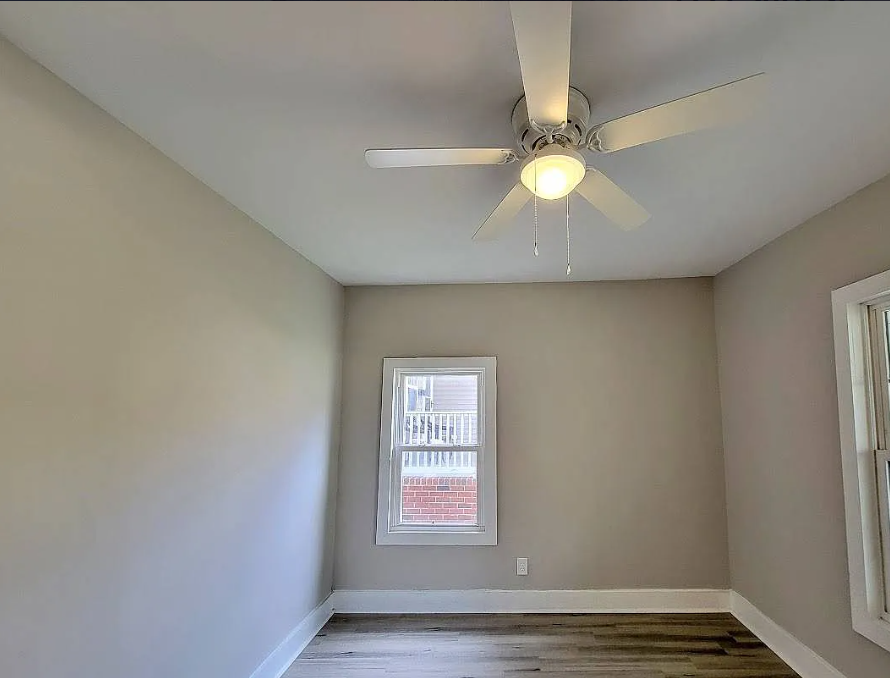 an empty room with a ceiling fan and a window