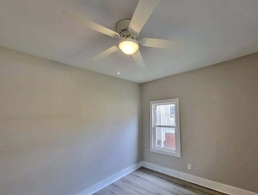 an empty room with a ceiling fan and a window