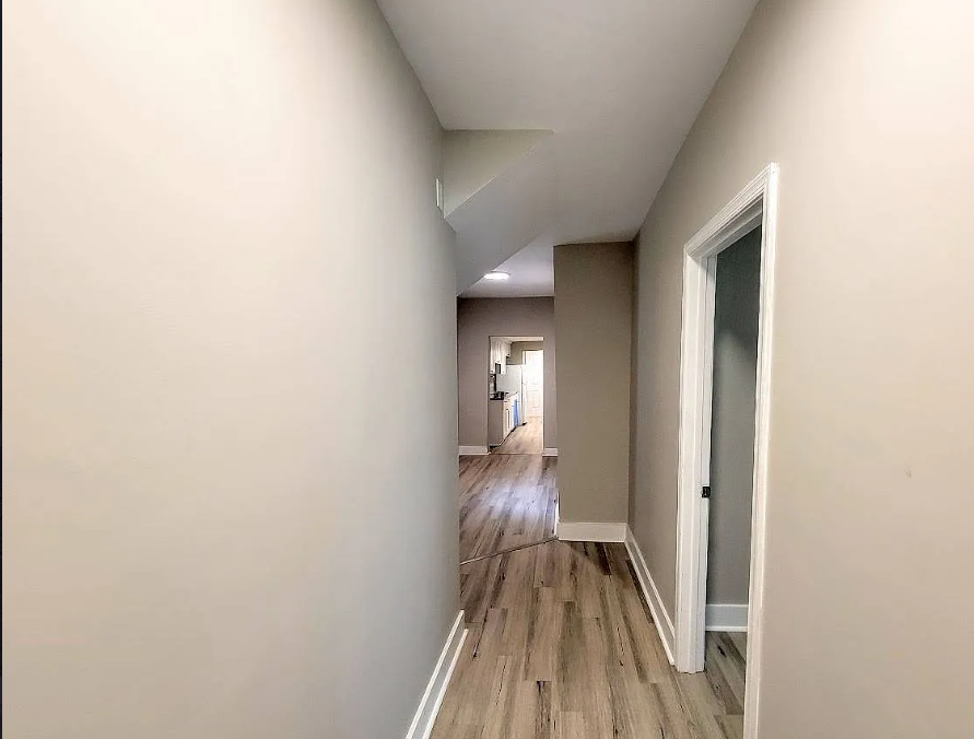 a hallway with a door to a room and a wooden floor