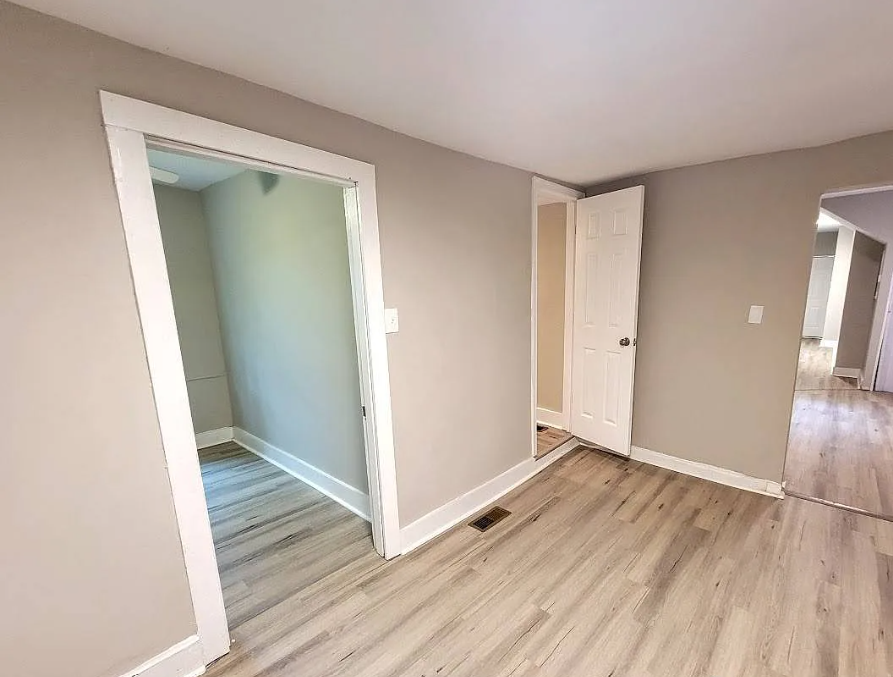 an empty room with wood floors and a mirror