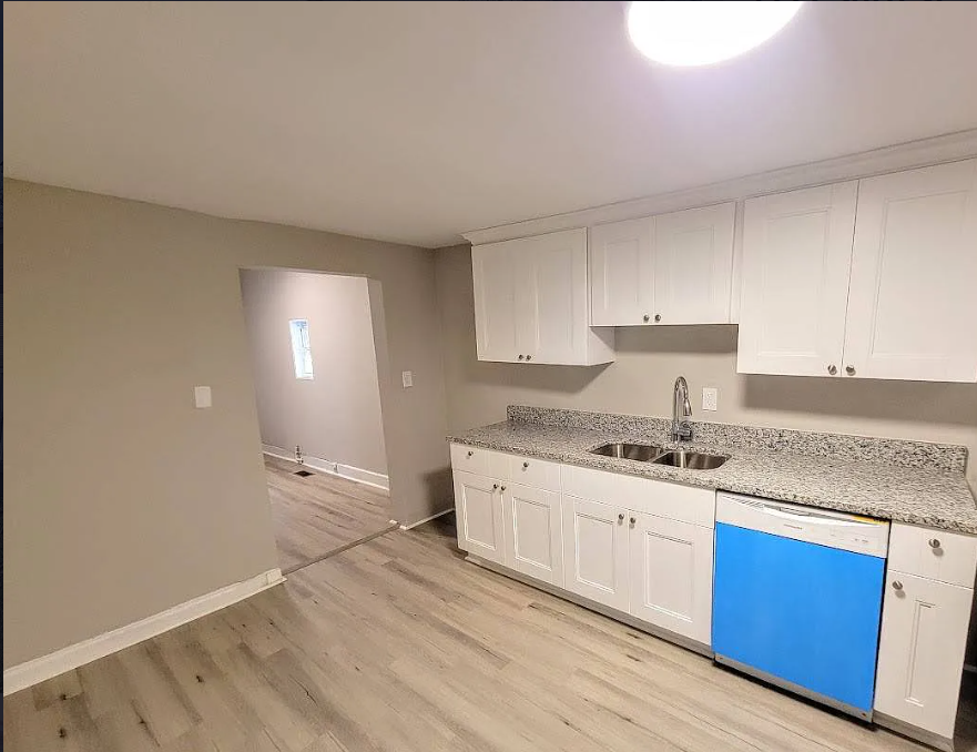 an empty kitchen with white cabinets and a blue dishwasher