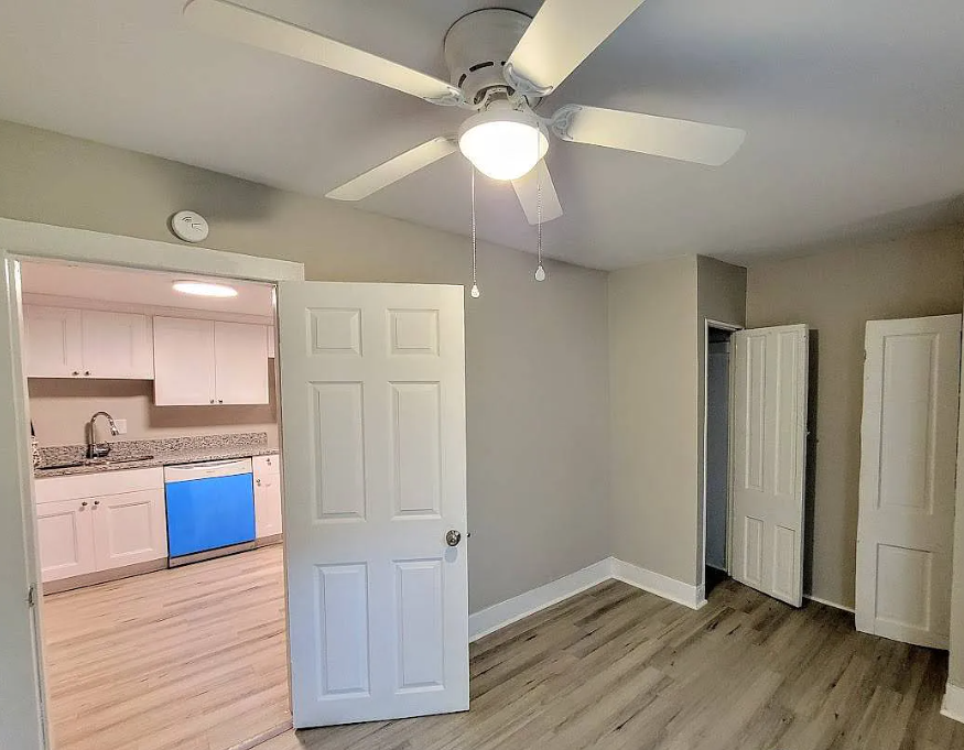 an empty living room and kitchen with a ceiling fan