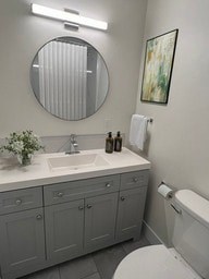 A bathroom with a white toilet, sink, and vanity.