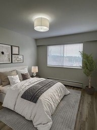 A bedroom with a bed, pillows, a lamp, a plant, and pictures on the wall.