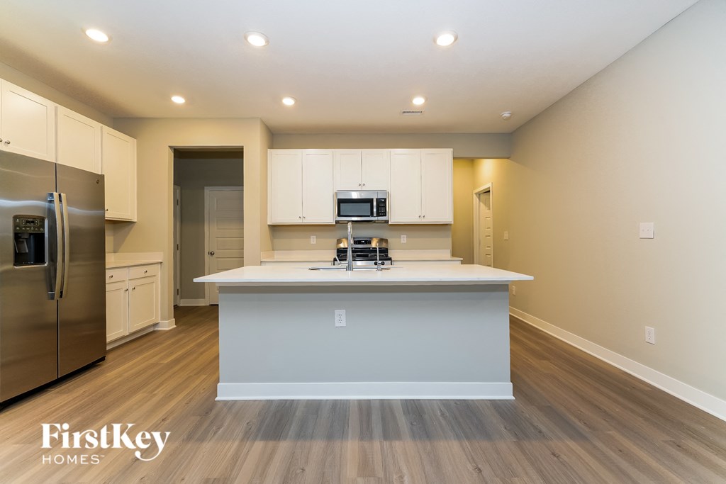 A kitchen with a refrigerator, microwave, and oven.