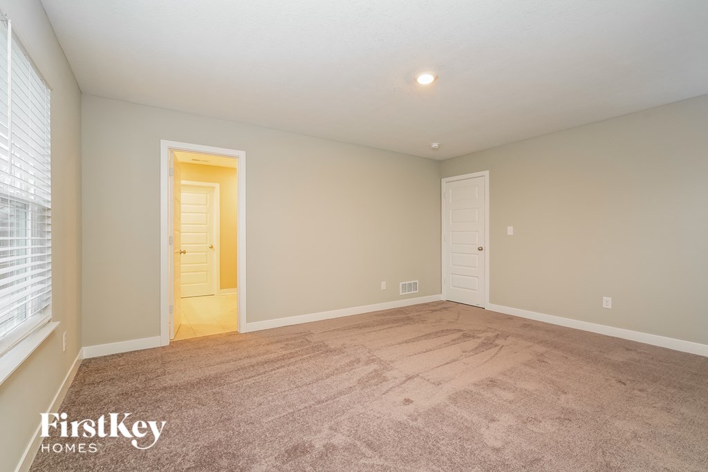 A room with a carpeted floor and a doorway leading to another room.