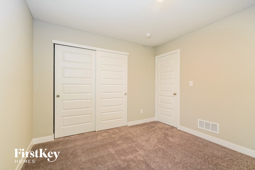 A room with two white doors and a carpeted floor.