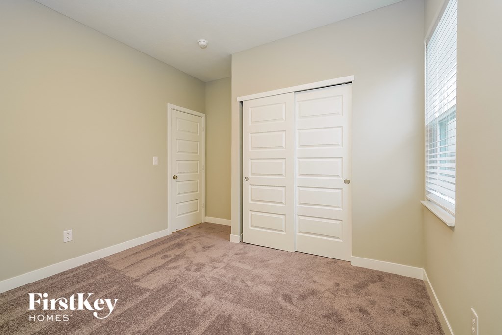 A room with a carpeted floor and two doors, one of which is closed.