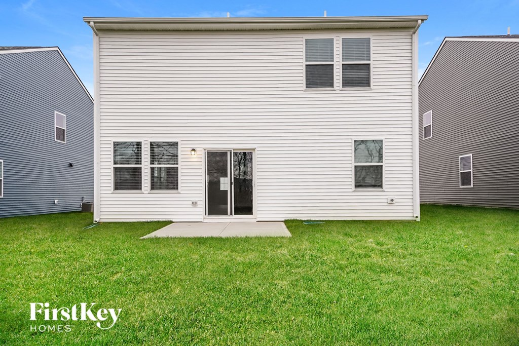 A white house with a black door and windows is in the foreground with a blue sky in the background.