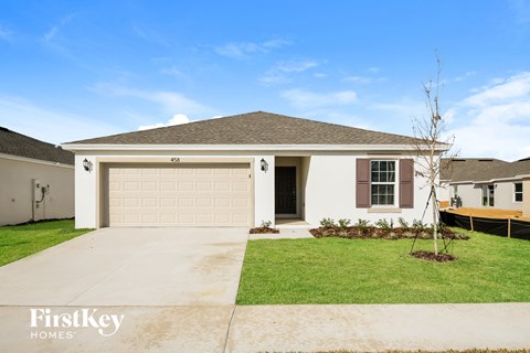 a beige house with a garage door and a lawn