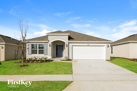 a beige house with a garage door and a lawn