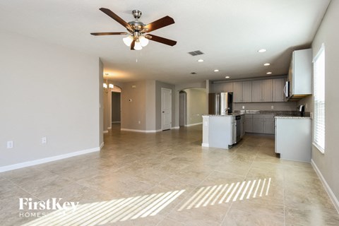 an empty kitchen and living room with a ceiling fan