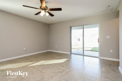 an empty living room with a ceiling fan and a sliding glass door
