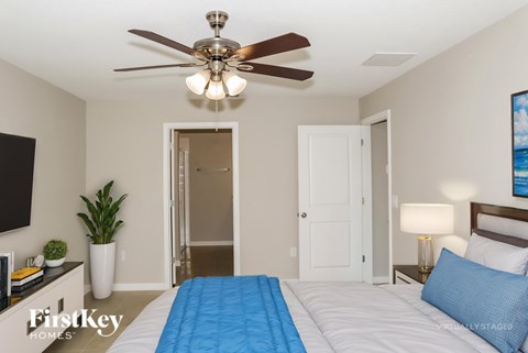 A bedroom with a bed, a ceiling fan, and a television.