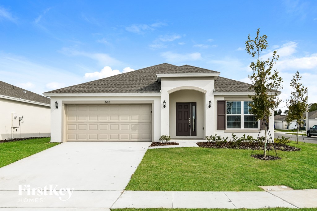 a white house with a garage door and a lawn