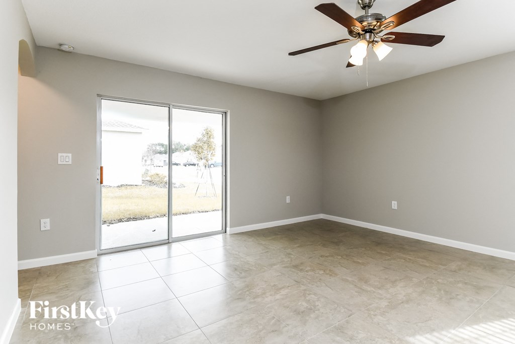 an empty living room with a ceiling fan and sliding glass doors