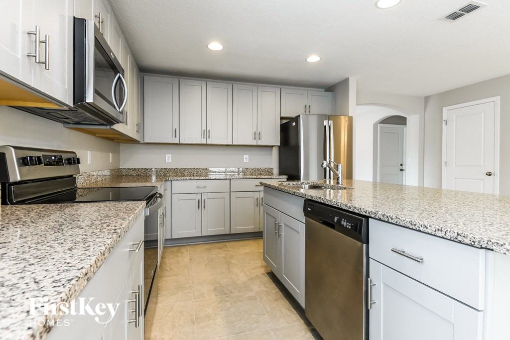 a white kitchen with granite counter tops and stainless steel appliances