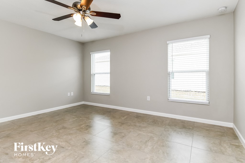 an empty room with a ceiling fan and two windows