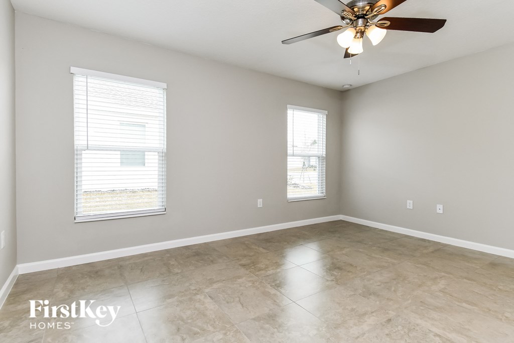 an empty room with a ceiling fan and two windows