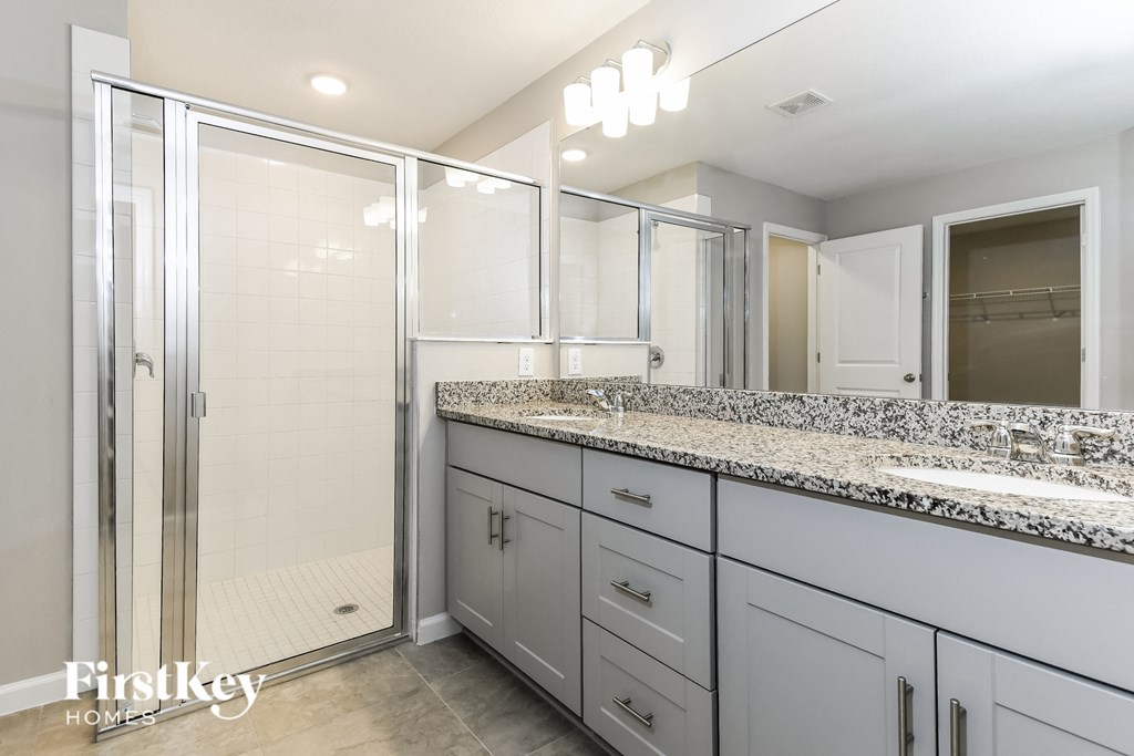 a white bathroom with granite counter tops and a shower