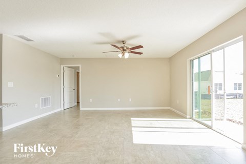 A spacious room with a ceiling fan and a sliding glass door.