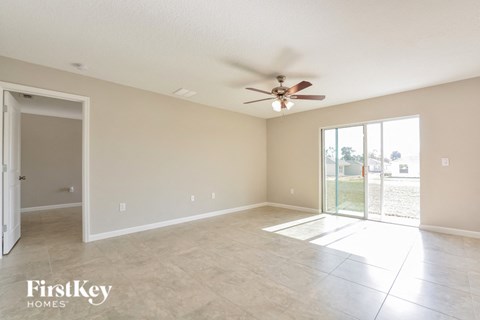 A spacious room with a ceiling fan and sliding glass doors.