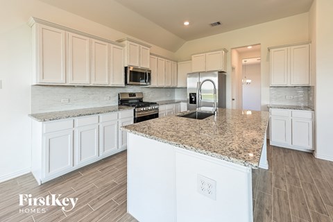 A kitchen with white cabinets and a granite countertop.