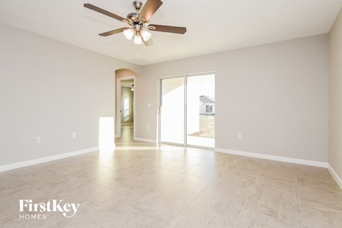 A spacious room with a ceiling fan and sliding glass doors.