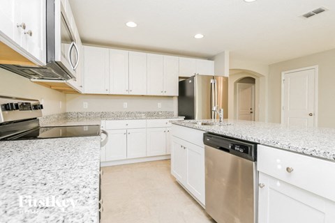 A kitchen with white cabinets and a granite countertop.