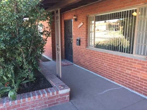 A brick building with a black door and a window with bars.