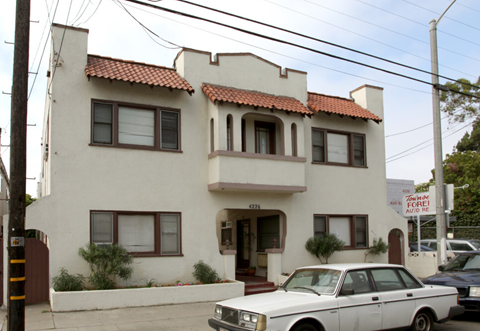 A white car is parked in front of a two-story house.