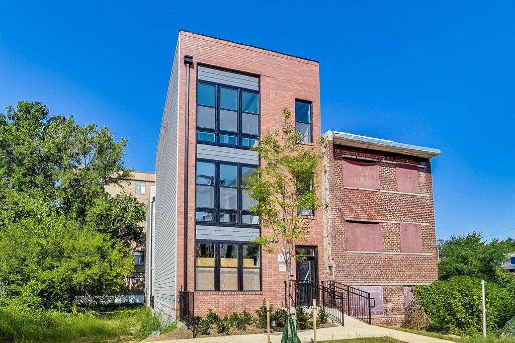 a brick building with large windows and a tree in front of it