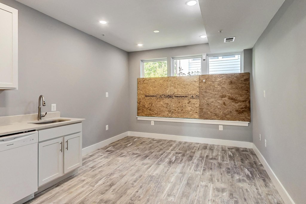 an empty kitchen with white cabinets and a sink and a wall with a large window