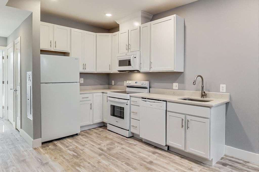 an empty kitchen with white cabinets and a sink and refrigerator