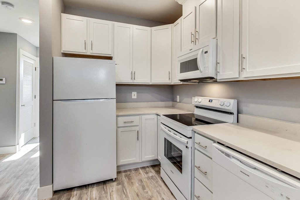 an empty kitchen with white cabinets and white appliances