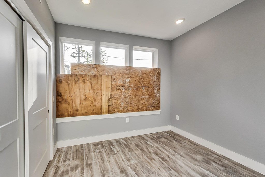an empty room with a boarded up window and a wall with a piece of wood