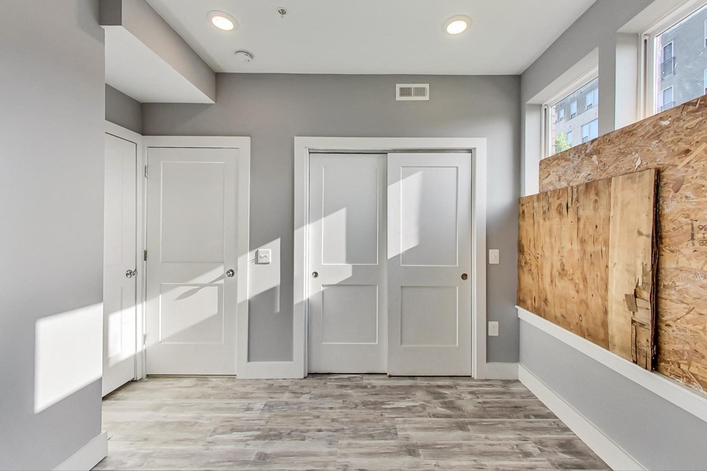a corridor with white doors and a wall with a boarded up door