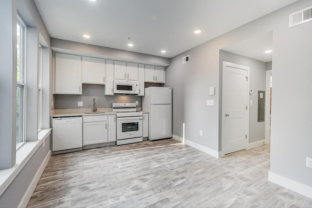 an empty kitchen with white appliances and white cabinets