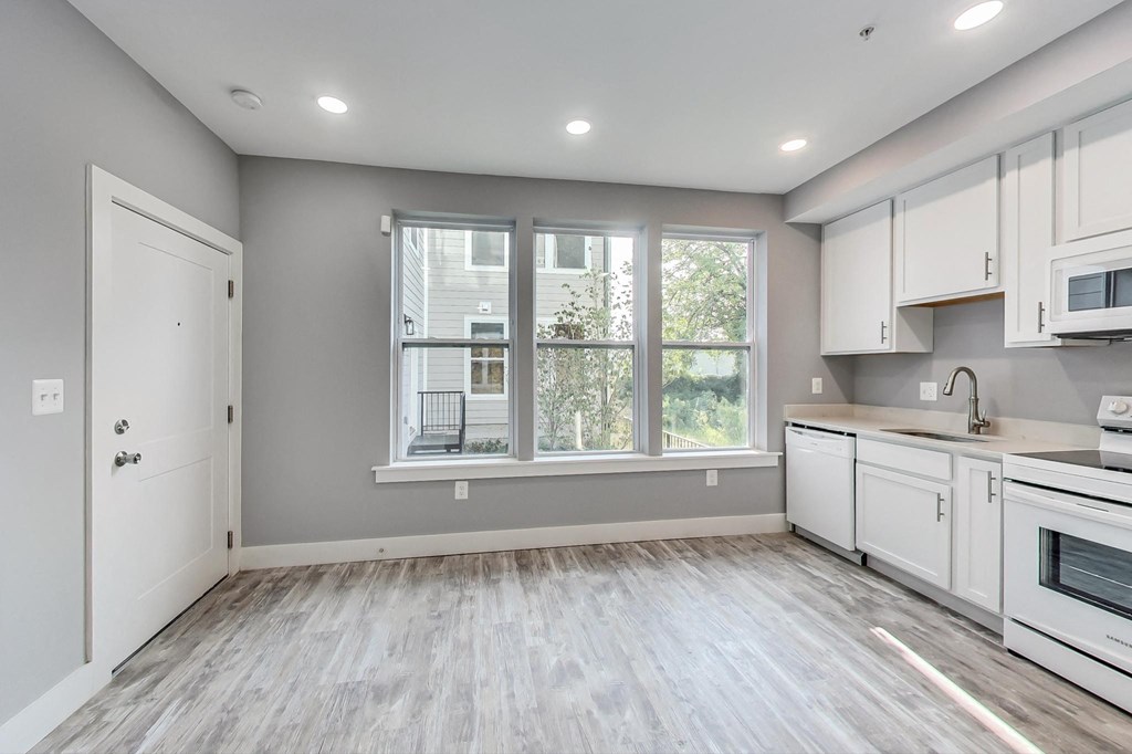 an empty kitchen with white cabinets and a large window