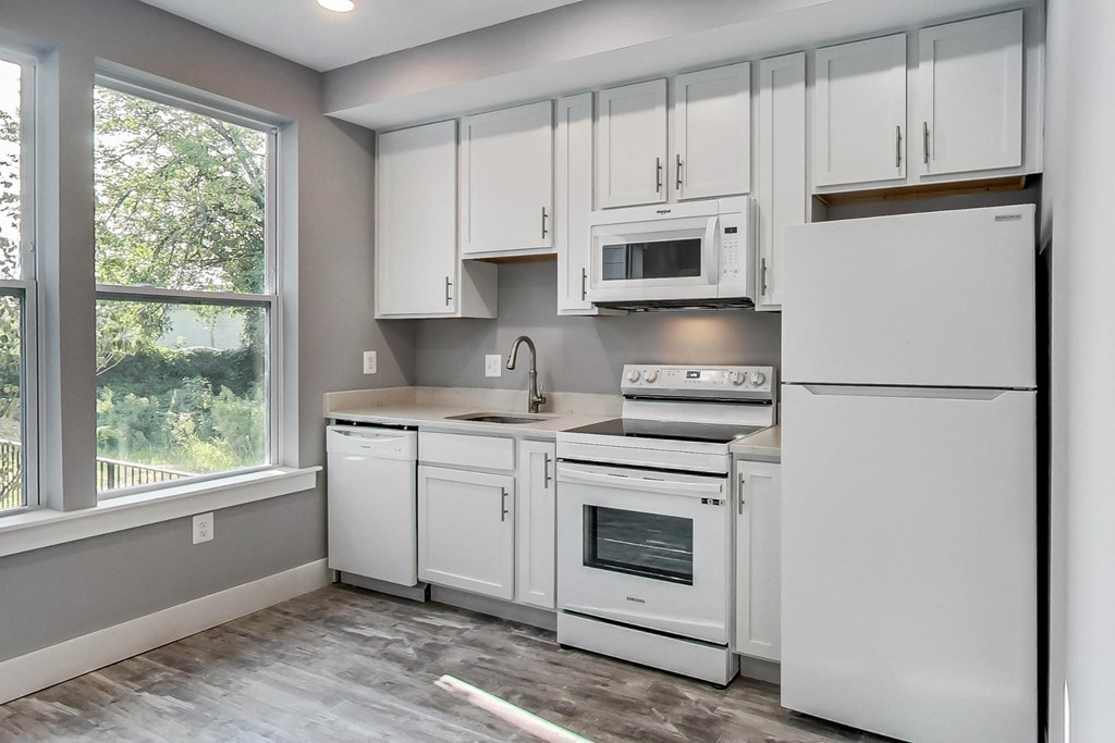an empty kitchen with white appliances and white cabinets