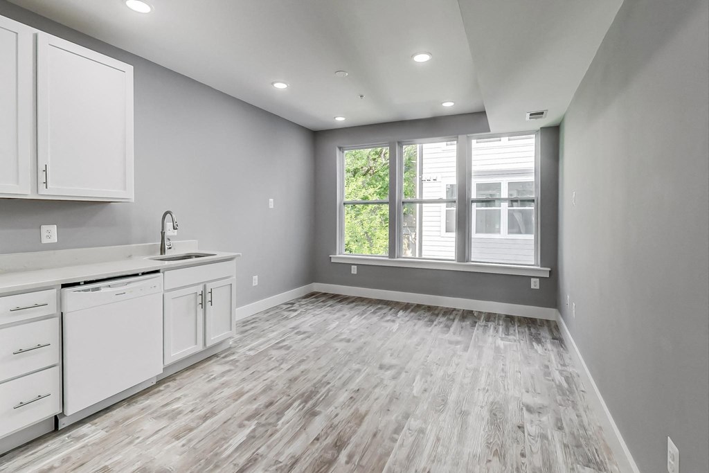 an empty kitchen with white cabinets and a large window