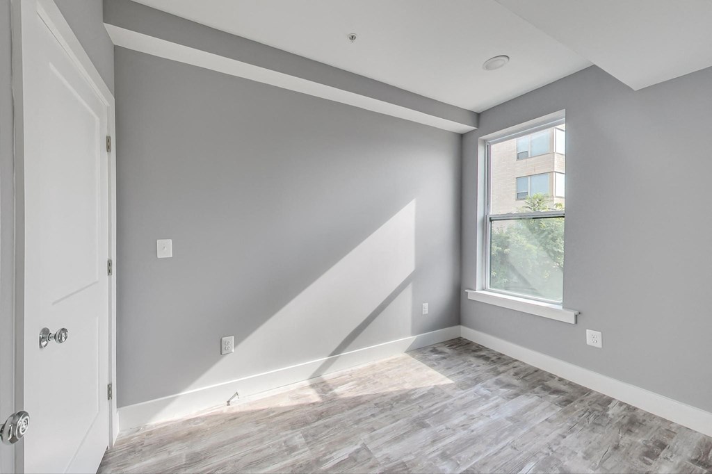 the living room of a new home with grey walls and a window