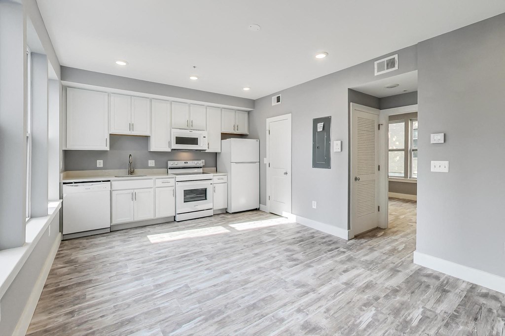 an empty kitchen with white cabinets and white appliances