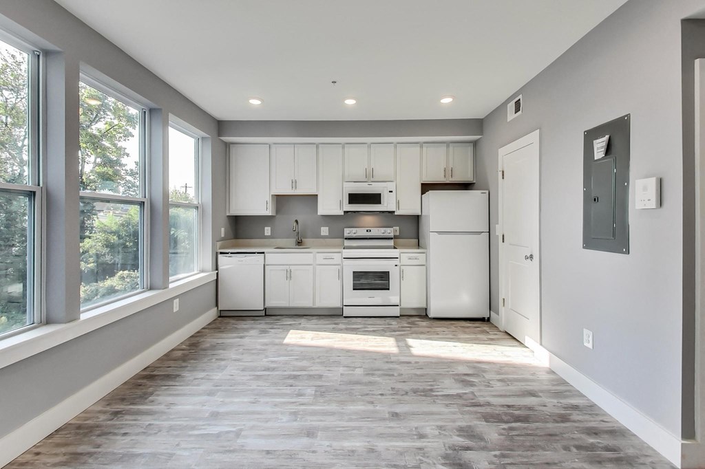 an empty kitchen with white appliances and a large window
