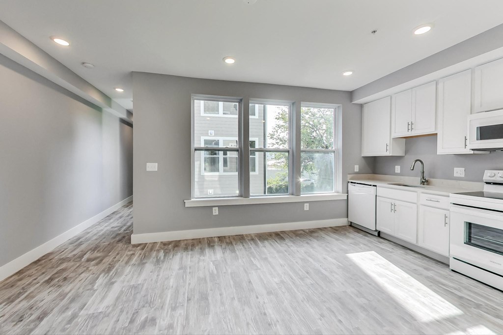 an empty kitchen with white cabinets and a window