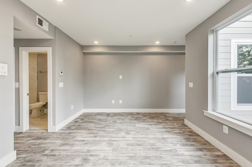 a renovated living room with a large window and a door to a bathroom