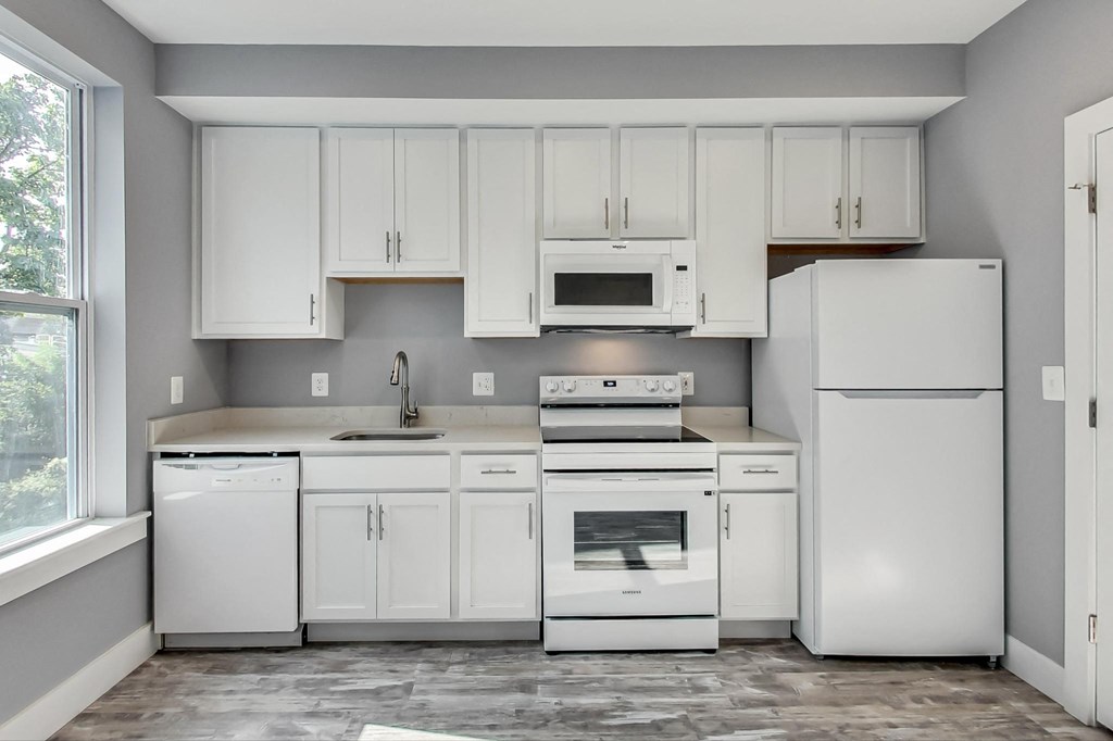 an empty kitchen with white appliances and white cabinets