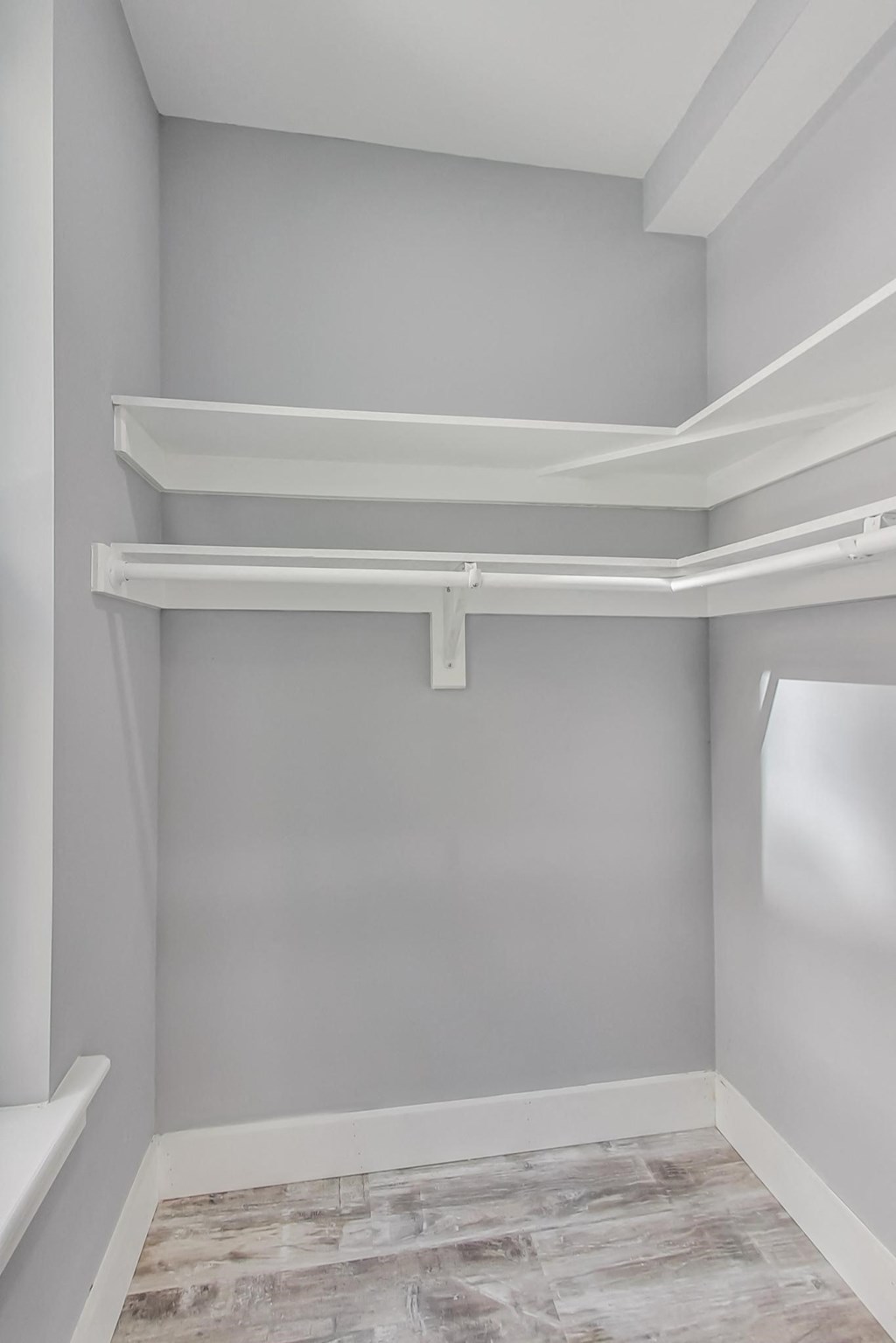 the closet in a new home with grey walls and a white shelf