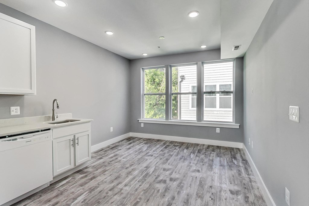 an empty living room with a window and a kitchen